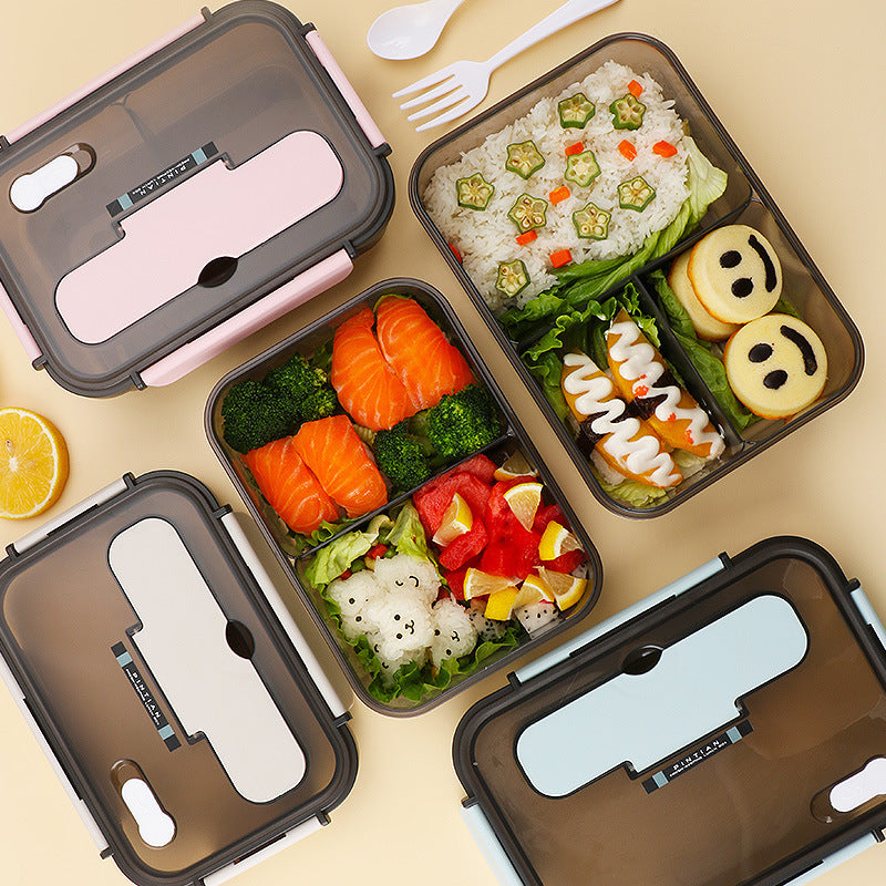 Filled FlowBox lunch boxes with salmon, vegetables, and fruit displayed on dining surface.
