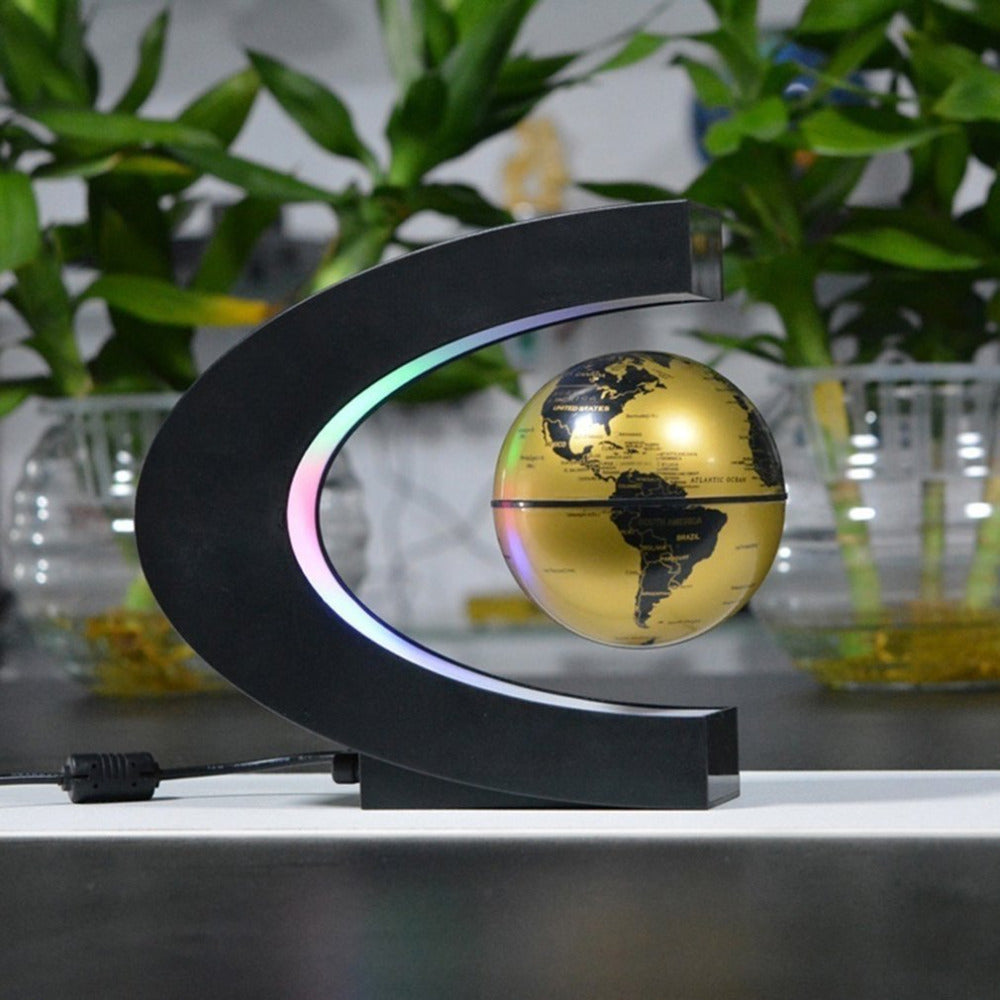 Levitating gold-toned globe floating within a crescent-shaped display frame.