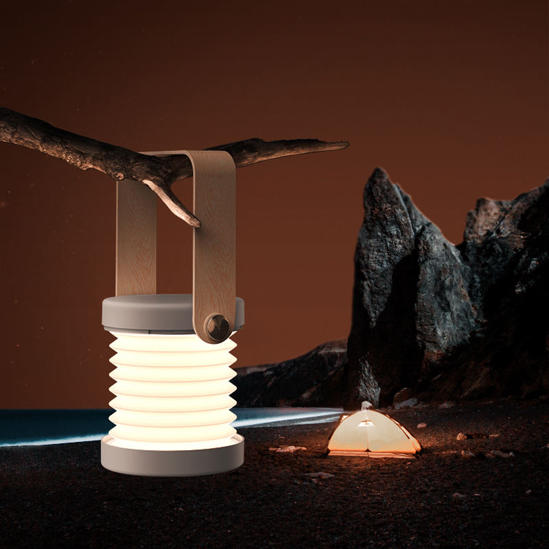 Lantern glowing beside rocks in nighttime outdoor environment showing portable design.