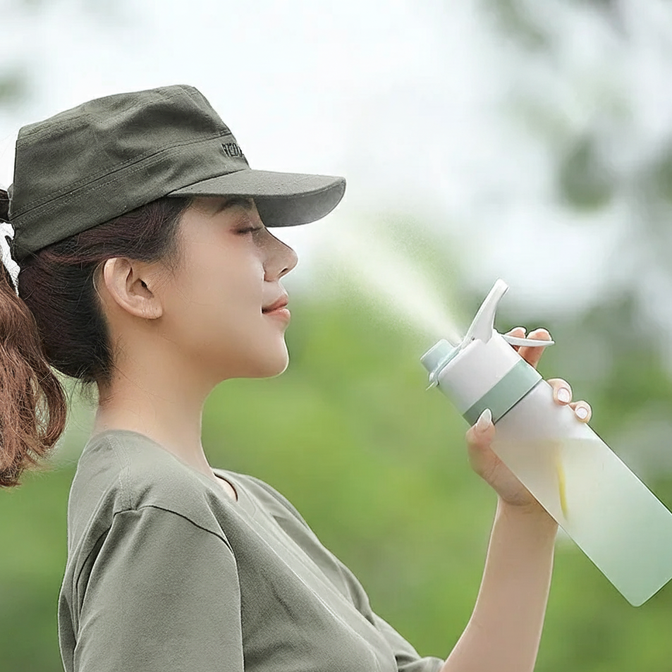 Woman misting her face with a spray water bottle outdoors.