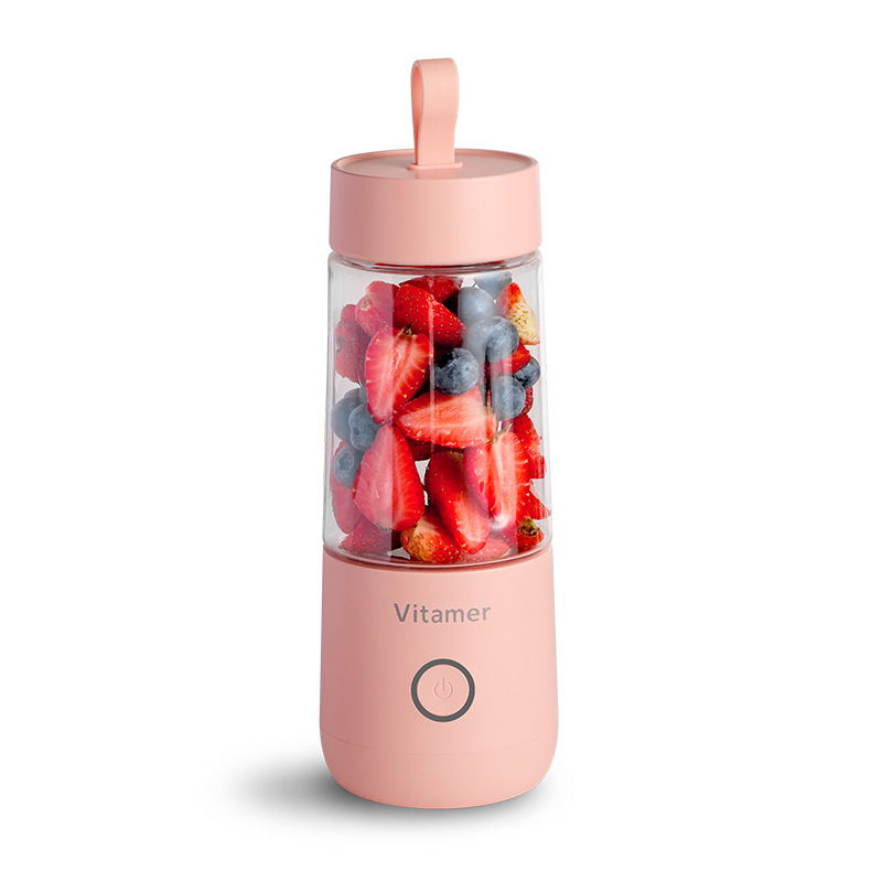 Portable electric blender in pink with fresh fruit inside blending cup.